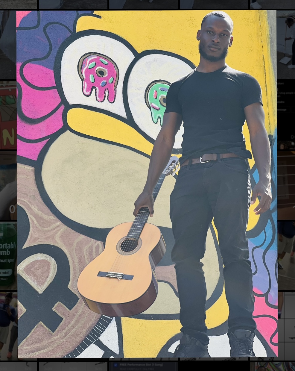 Man standing next to a colorful mural with a guitar, cartoon characters, and abstract shapes, outdoors during daytime.