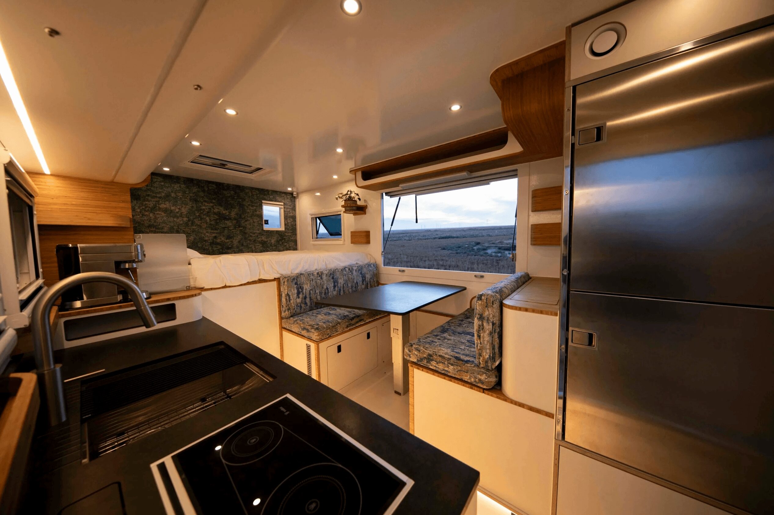 Interior of a modern boat or yacht with seating area, window view, and kitchen appliances.