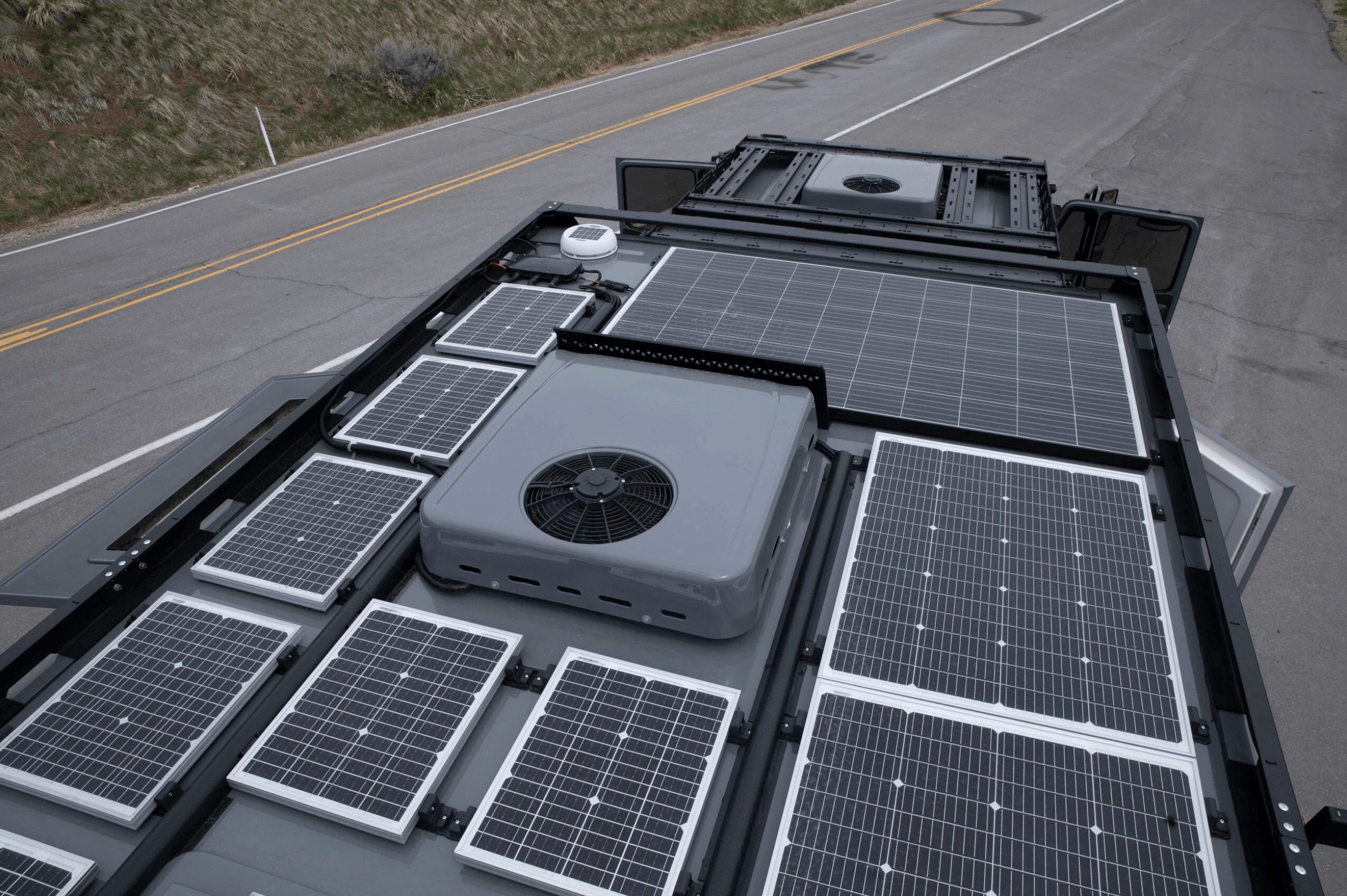 Roof with multiple solar panels and a large ventilation fan, on a street with a double yellow line.