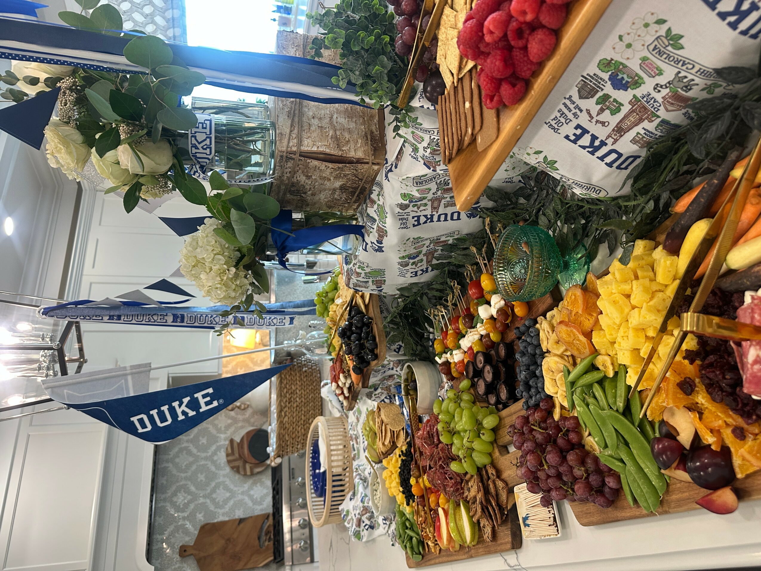Display of fruits, vegetables, and flowers on a table with a Duke banner in the background.