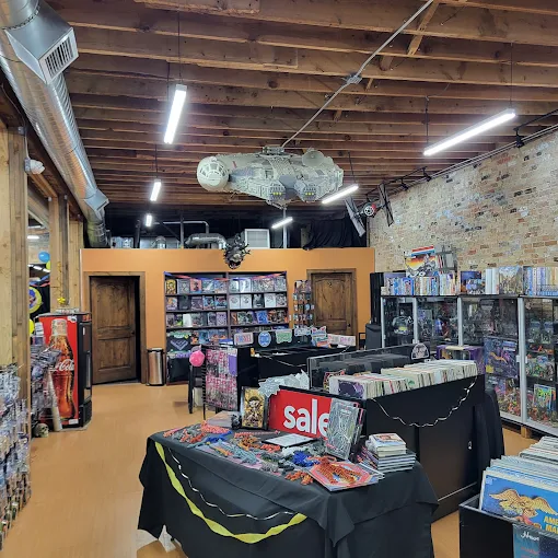 Bookshelves filled with DVDs and books in a store with wooden ceiling and brick wall, sale sign on table, bright lighting.