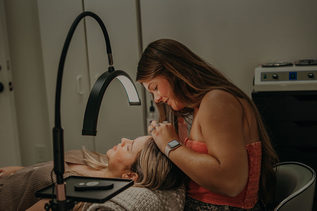 Woman leaning over a person lying in a medical bed, with medical equipment nearby.