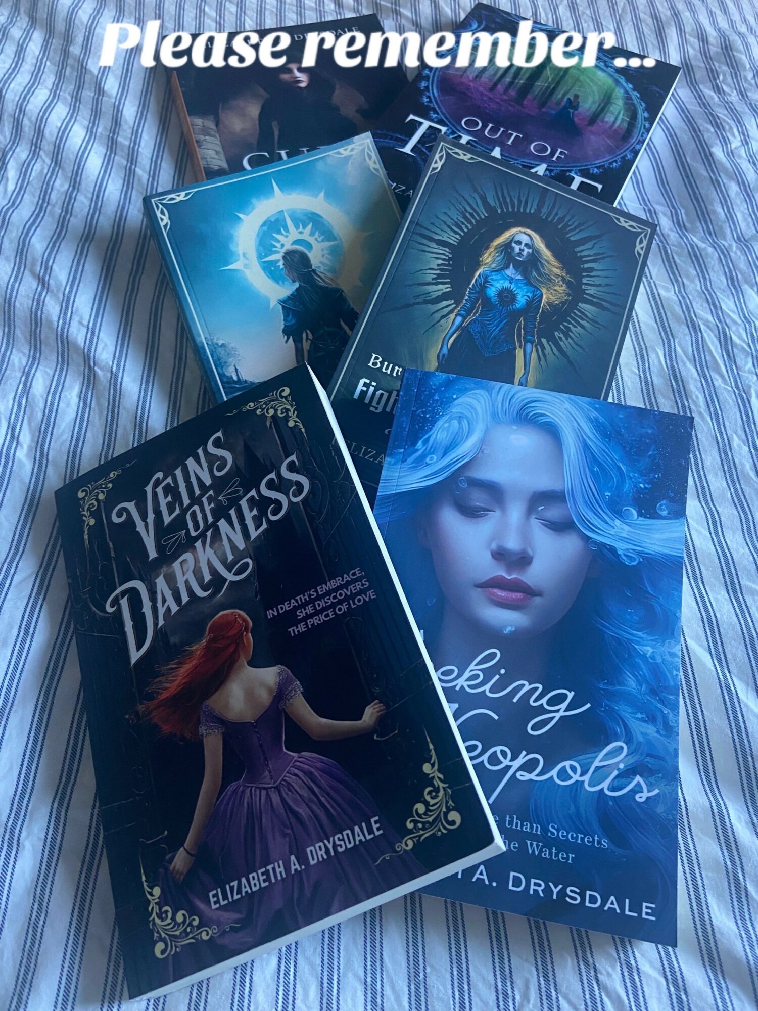 Five books with colorful covers are arranged on a striped fabric surface, featuring illustrations of women and celestial themes.