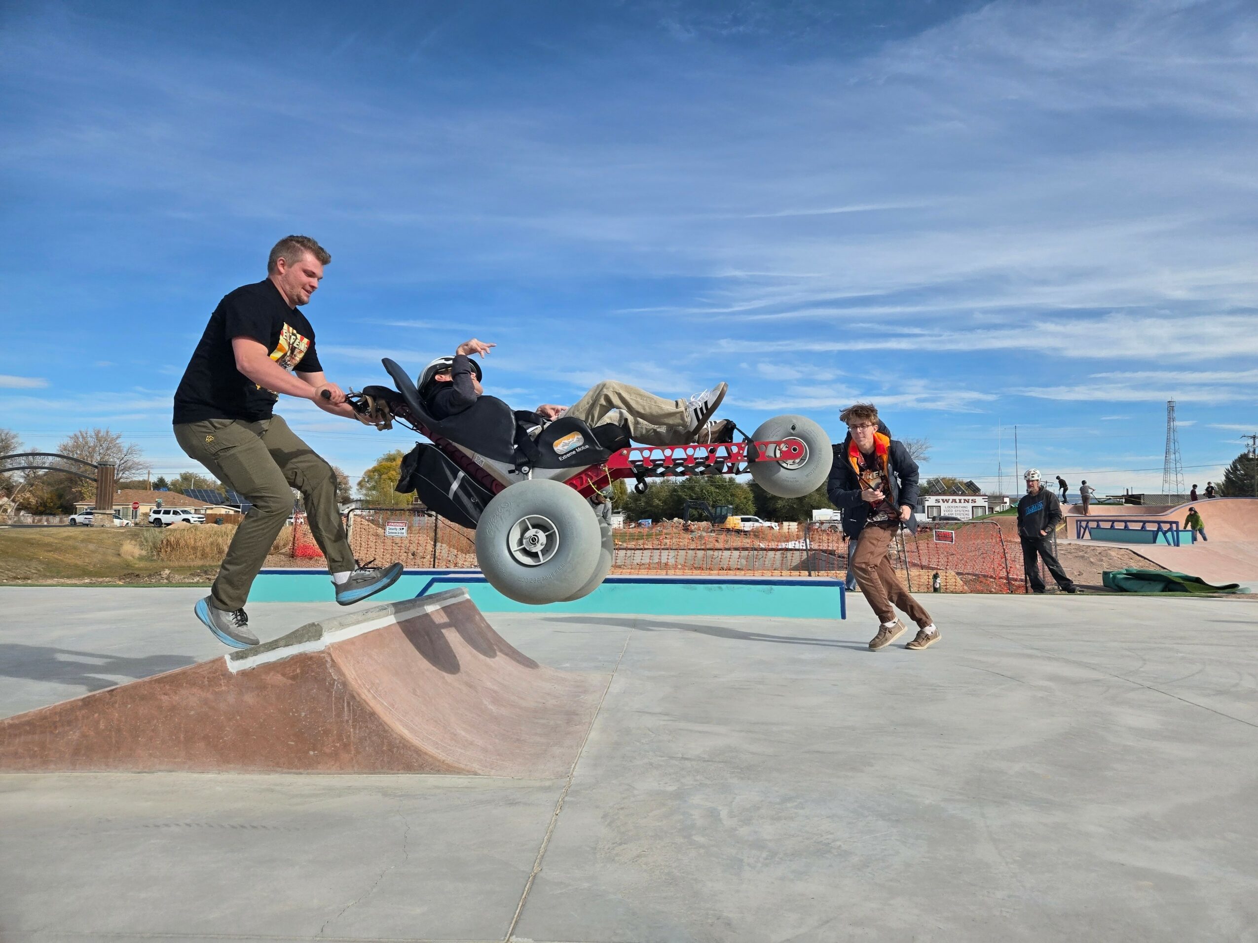 Person riding a motorized skateboard at a skate park with a blue sky background.