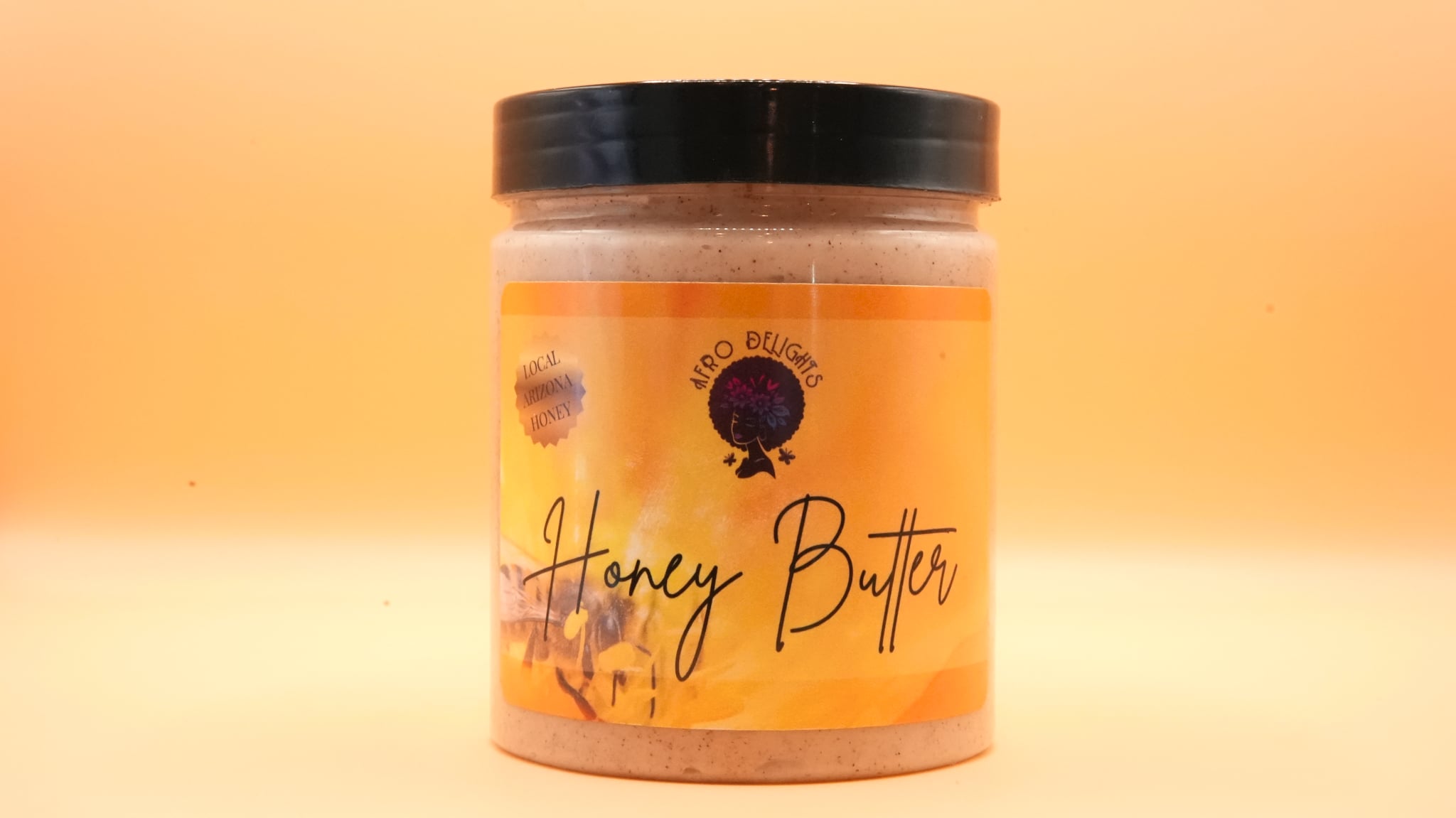 Container of honey butter with a black lid and a yellow label featuring a black logo and text.