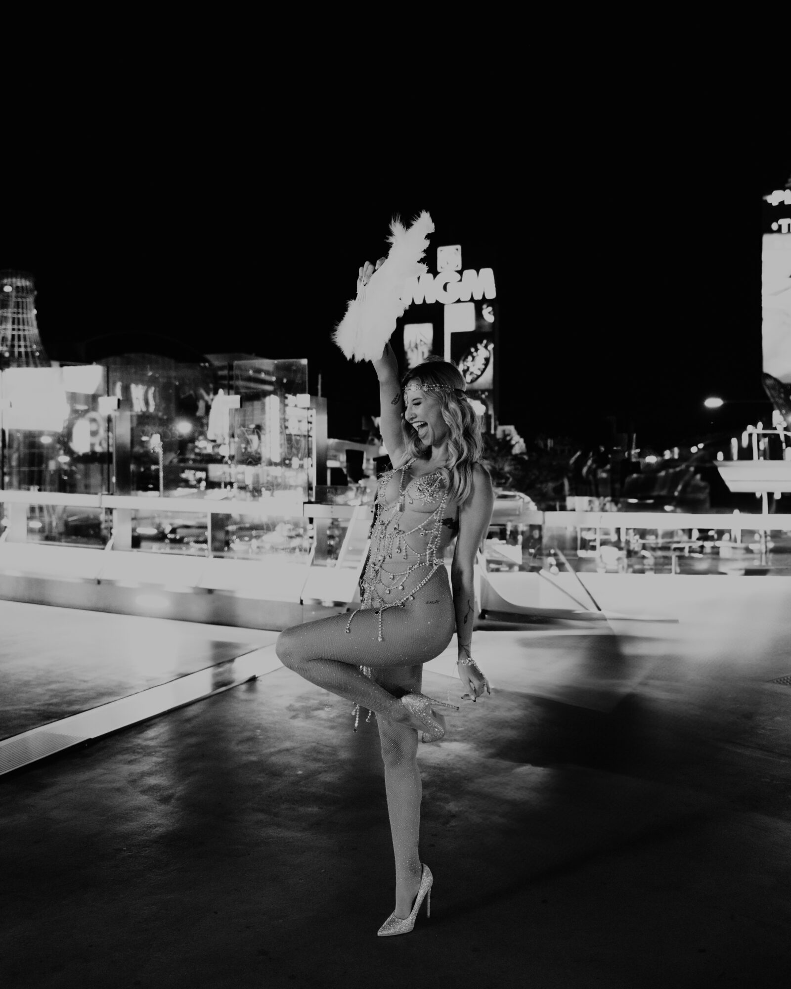 Woman standing on one leg with a city skyline in the background at night, illuminated signs and buildings visible.