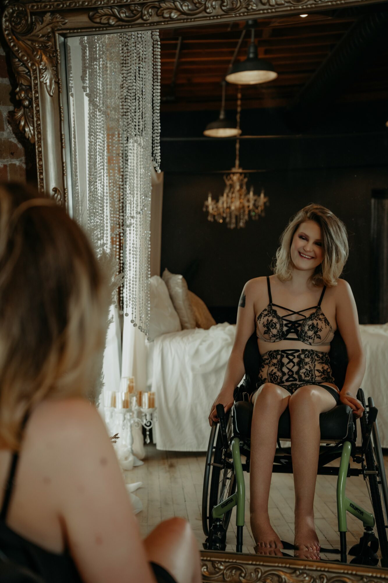 Two women in a room with elegant decor, one sitting in a wheelchair and smiling, the other with her back to the camera.