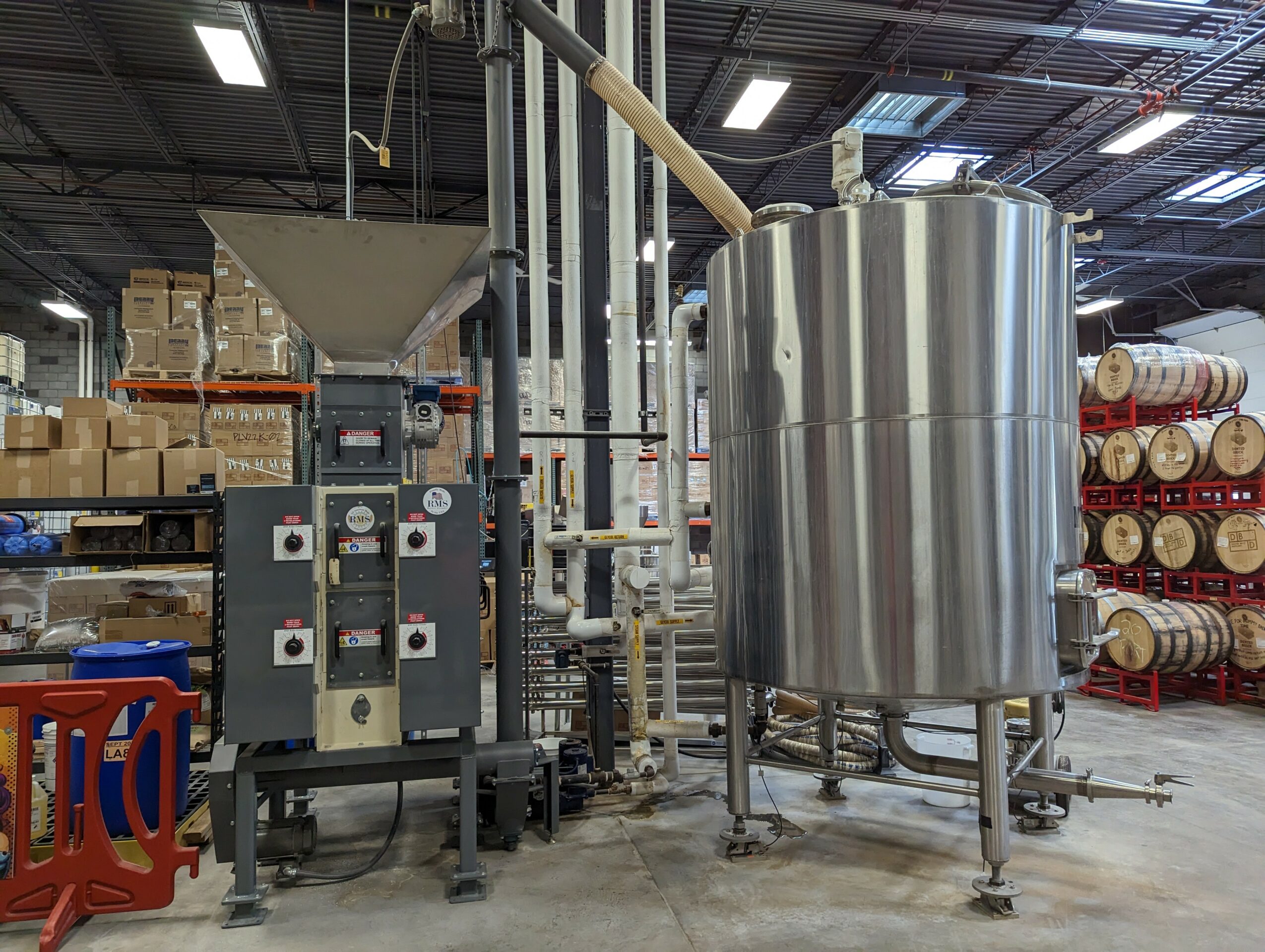 Industrial equipment with large stainless steel tank and control panel in a warehouse setting.