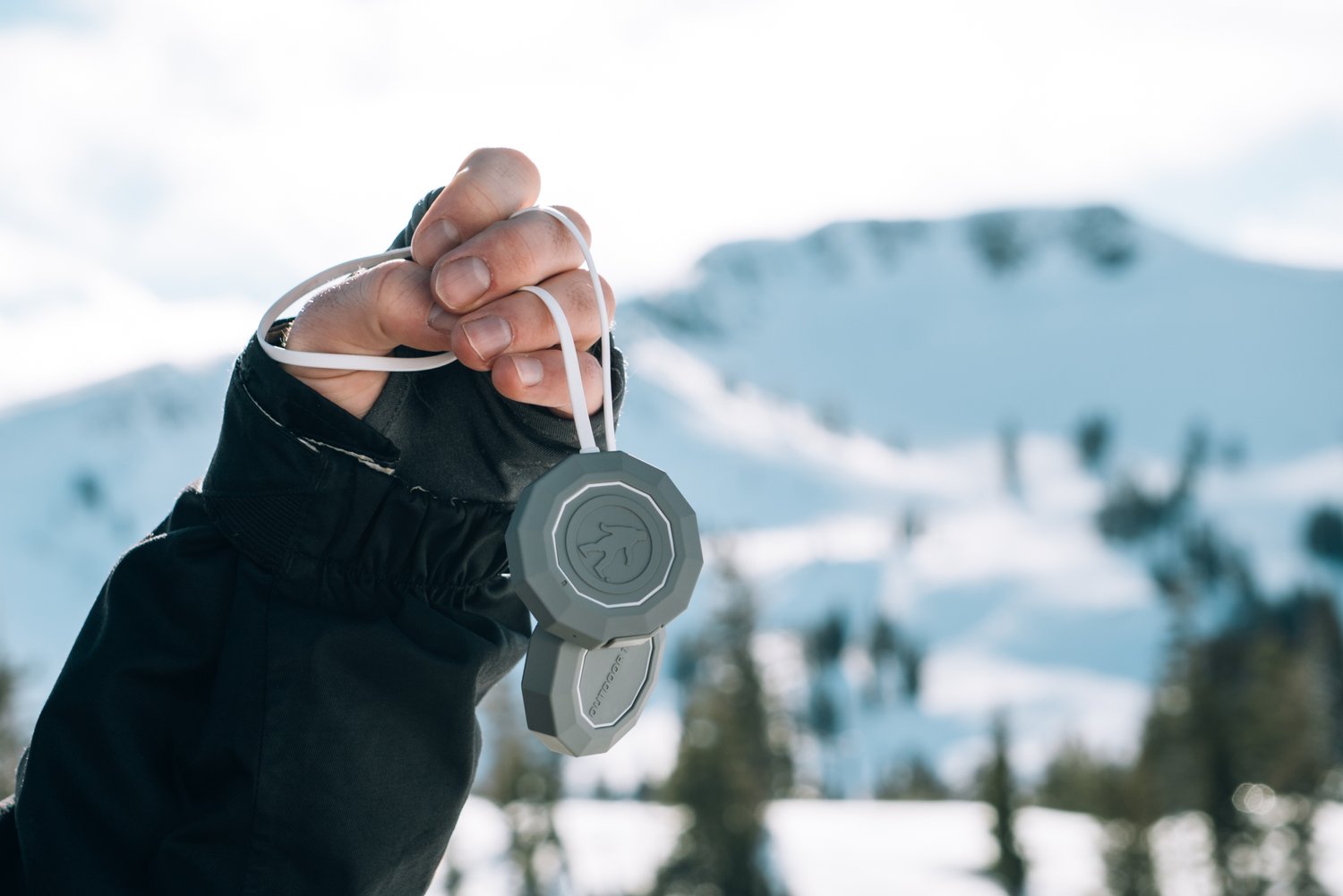 Person holding a stopwatch outdoors with snowy mountains in background