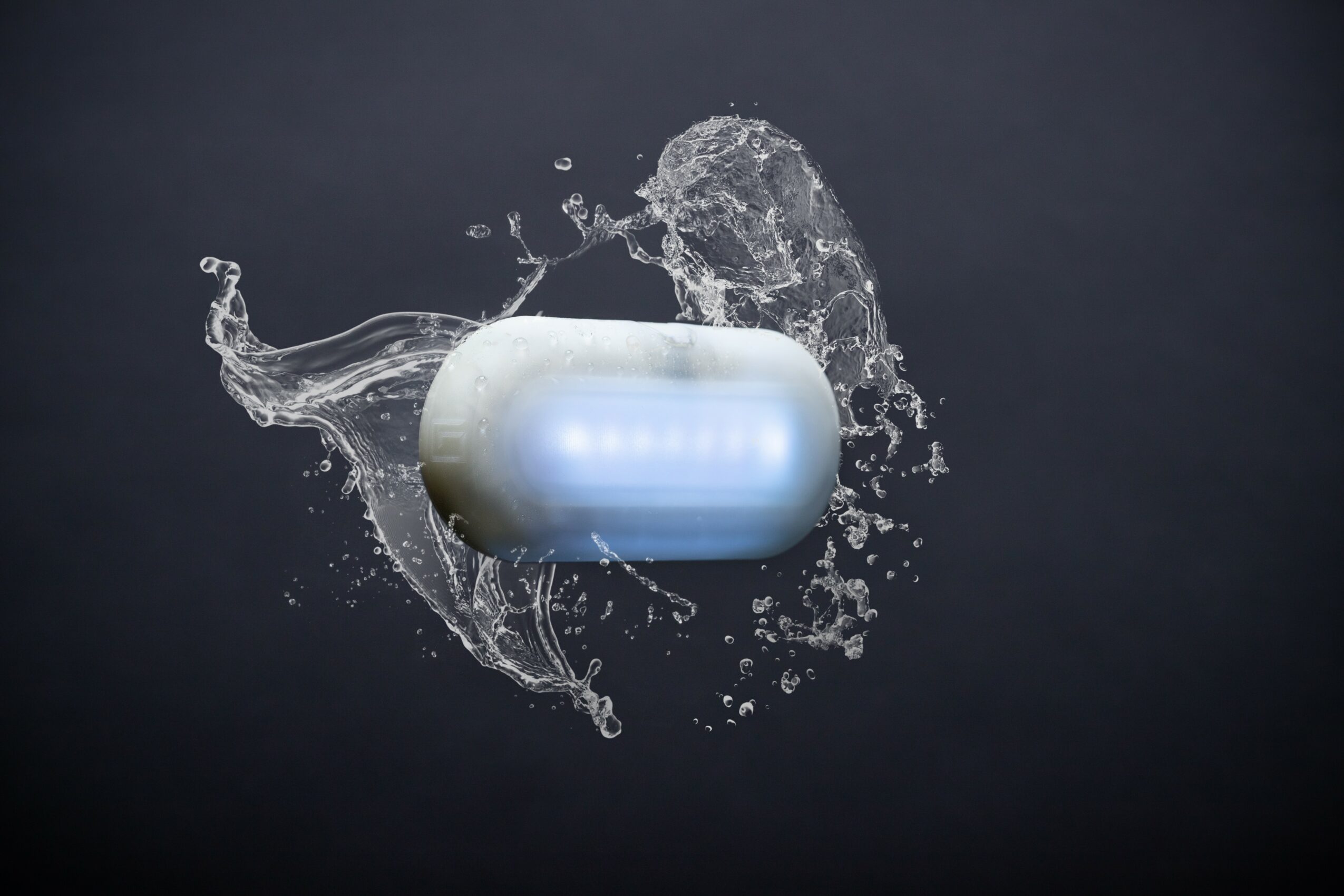 A capsule pill surrounded by splashing water on a dark background.