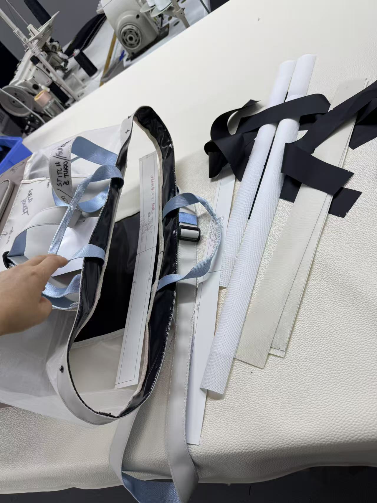 Various rolled and flat materials, including black and white strips, on a white surface in a workspace.