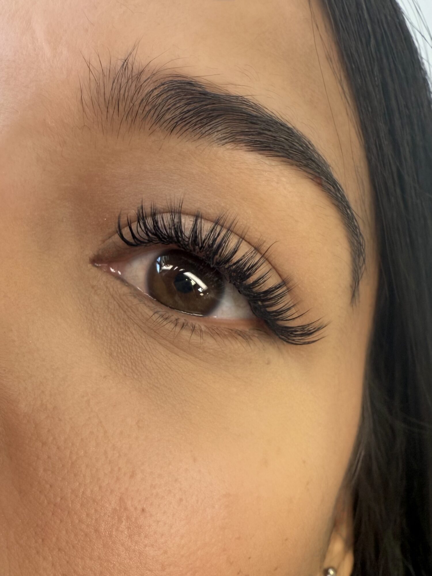 Close-up of a person's eye with long eyelashes and well-groomed eyebrow.